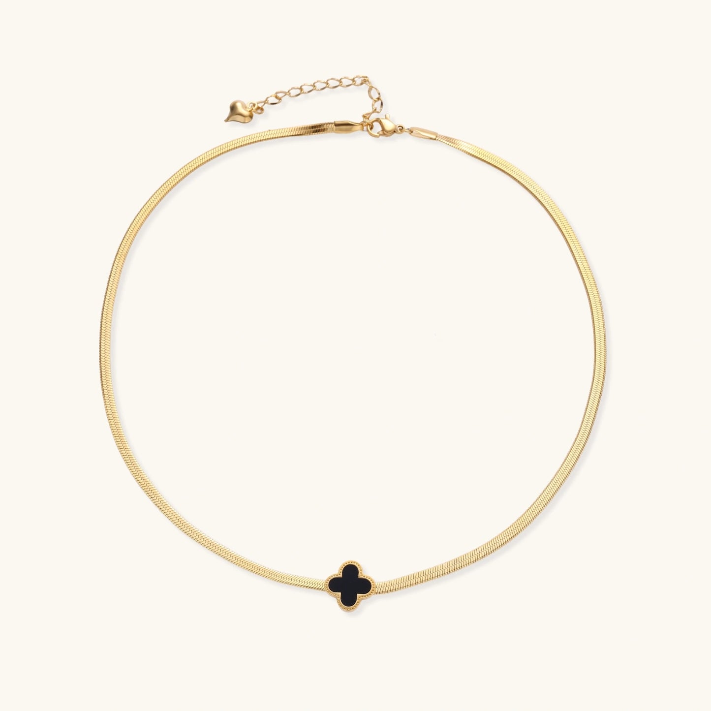 Dainty 18K gold-plated herringbone chain necklace with black enamel quatrefoil clover pendant on white background